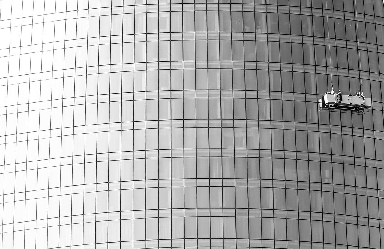 Glass high-rise facade with a suspended platform used for window cleaning.